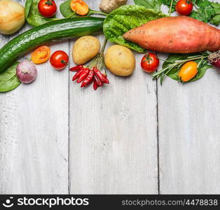 Fresh organic farm vegetables and ingredients for healthy cooking on white wooden background, border, top view. Vegetarian or diet food concept