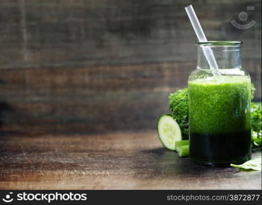 Fresh organic green smoothie with spinach, cucumber, parsley, celery and lemon on wooden background