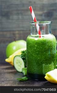 Fresh organic green smoothie with spinach, cucumber, parsley, celery and lemon on wooden background