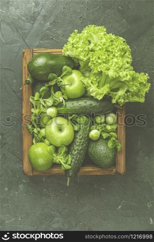 Fresh organic green vegetables and fruits on green background. Spring diet, healthy raw vegetarian, vegan concept, detox breakfast, alkaline clean eating. Copy space.