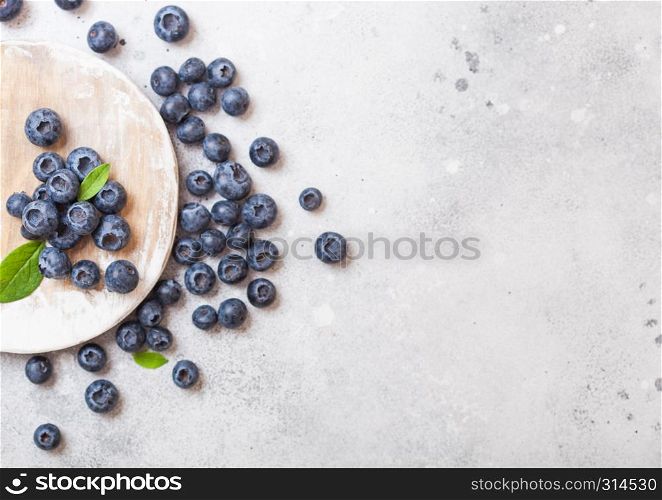 Fresh organic raw blueberries on round wooden board on stone kitchen table