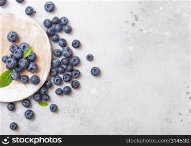Fresh organic raw blueberries on round wooden board on stone kitchen table