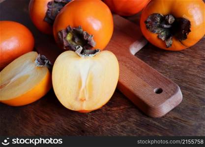 Fresh organic ripe Persimmons fruits with slice on old wooden table background. Top view. Flat lay. Copy space for text and content.. Fresh organic ripe Persimmons fruits with slice on old wooden table background. Top view. Flat lay. Copy space for text and content