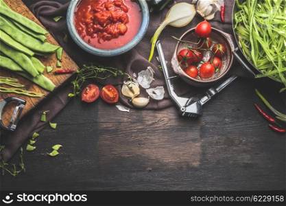 Fresh organic seasonal vegetables on dark rustic wooden background. Tomatoes , Green french beans and cooking ingredients for tasty vegetables dish. Vegan and healthy food concept