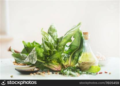 Fresh organic spinach bunch with olives oil bottle lies on kitchen table at light background. Healthy cooking concept