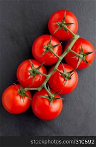 Fresh organic tomatoes on black stone board . For kitchen