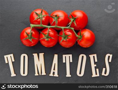 Fresh organic tomatoes on black stone kitchen board. For kitchen