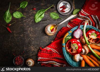 Fresh organic vegetables and seasoning ingredients in basket on rustic kitchen table with spoon and oil. Healthy food or vegetarian food concept.