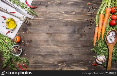 Fresh organic vegetables and spoons on rustic  wooden background, top view, border. Healthy food or vegetarian cooking concept