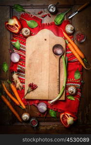 Fresh organic vegetables around old cutting board with wooden spoon on rustic napkin and wooden background. Top view, frame. Vegetarian or Healthy food concept.
