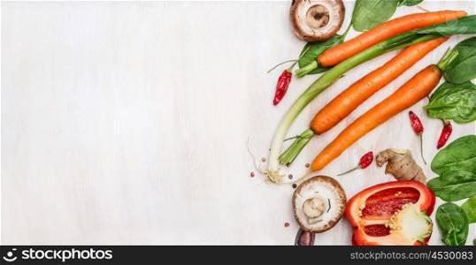 Fresh organic vegetables ingredients for tasty cooking on white wooden background, top view, place for text. Healthy food and diet concept.