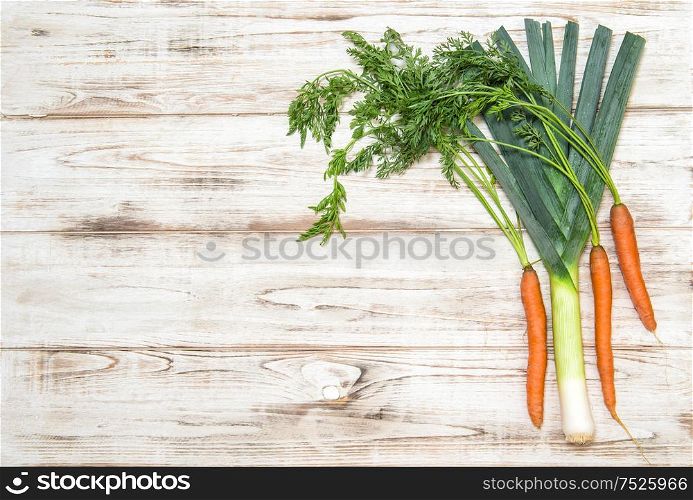 Fresh organic vegetables. Leek and carrots on wooden background. Healthy food ingredients