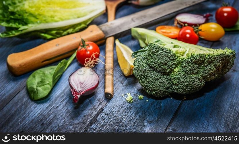 Fresh organic vegetables with kitchen knife on blue wooden background, close up