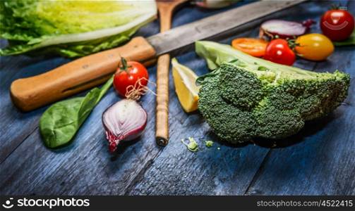 Fresh organic vegetables with kitchen knife on blue wooden background, close up