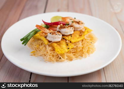 Fresh Pad Thai Shrimp with lime, lettuce, omelet and spring onions in a white plate on wooden.