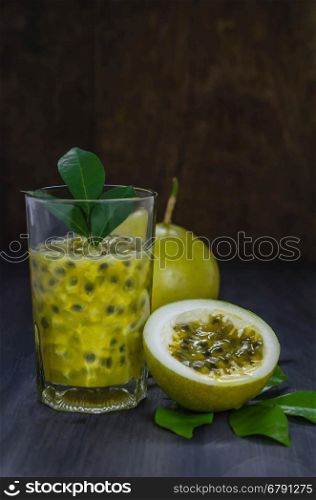 Fresh passion fruit juice in glass with passion fruits over wooden background , still life