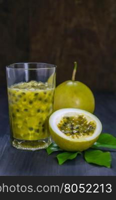 Fresh passion fruit juice in glass with passion fruits over wooden background , still life