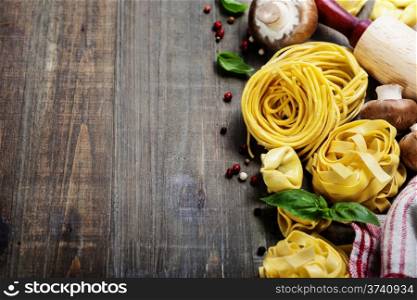 Fresh pasta and italian ingredients on wooden table