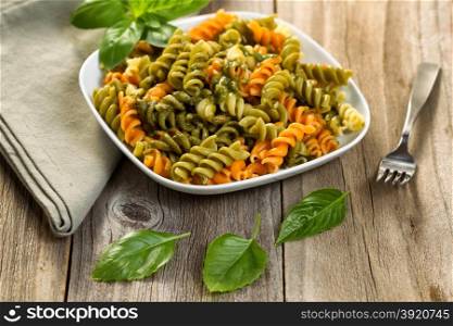 Fresh pasta with and fusilli noodles and basil pesto, selective focus on front part of dish.