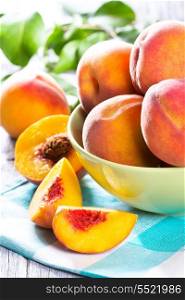 fresh peaches with leaves on wooden table