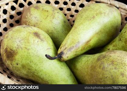 Fresh pears in wicker plate on black