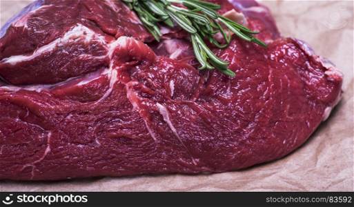 fresh piece of beef meat with a sprig of rosemary, close up