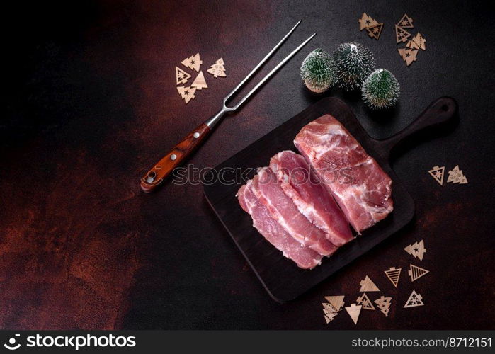 Fresh piece of raw pork with spices, salt and herbs on a wooden cutting board. Cooking grilled meals at home. Fresh piece of raw pork with spices, salt and herbs on a wooden cutting board