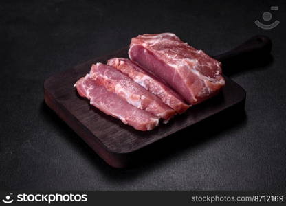 Fresh piece of raw pork with spices, salt and herbs on a wooden cutting board. Cooking grilled meals at home. Fresh piece of raw pork with spices, salt and herbs on a wooden cutting board