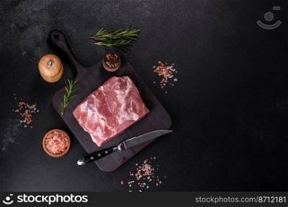 Fresh piece of raw pork with spices, salt and herbs on a wooden cutting board. Cooking grilled meals at home. Fresh piece of raw pork with spices, salt and herbs on a wooden cutting board