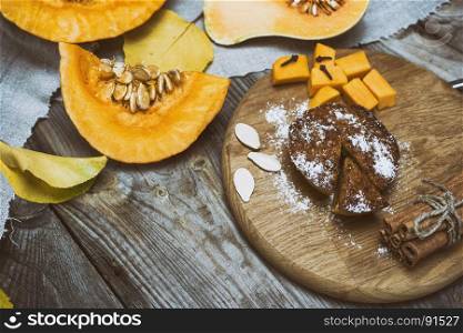 fresh pieces of pumpkin and pumpkin cake on a wooden board, empty space in the middle