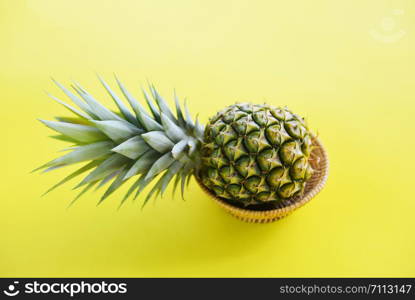 Fresh pineapple fruit in a basket on yellow background