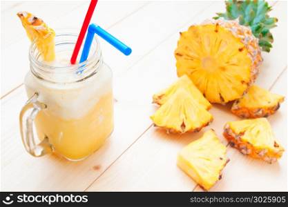 Fresh pineapple smoothie with pineapple slice on wooden table