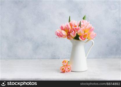 fresh pink and yellow tulips in white vase on gray background. Pink and yellow tulips