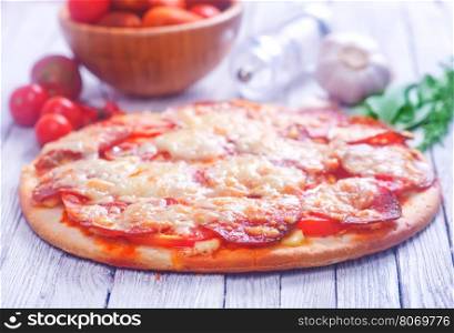 fresh pizza with salami and cheese on a table