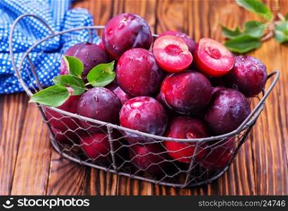 fresh plums in basket and on a table