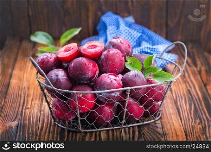 fresh plums in basket and on a table