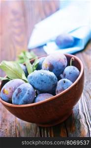 fresh plums in bowl and on a table