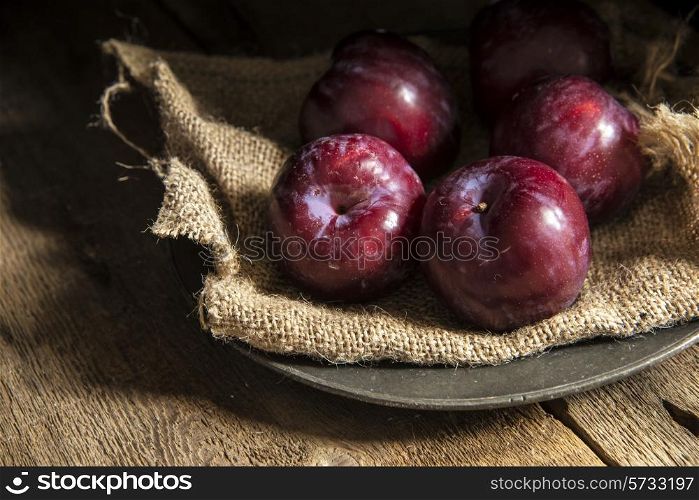 Fresh plums in natural light setting with moody vintage style. food, fresh, raw, fruit, vegetables, wood, wooden, background, grunge, retro, vintage, moody, dark,
