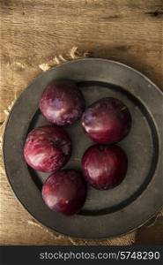 Fresh plums in natural light setting with moody vintage style