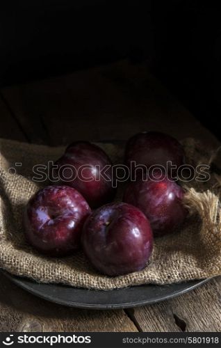 Fresh plums in natural light setting with moody vintage style