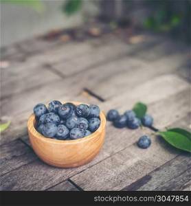 Fresh plums in wooden bowl on old wooden background