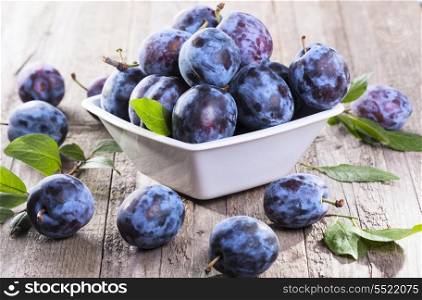 fresh plums with leaves on wooden table