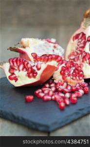 Fresh pomegranate sliced and ripped with seeds showing in rustic setting