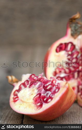 Fresh pomegranate sliced and ripped with seeds showing in rustic setting