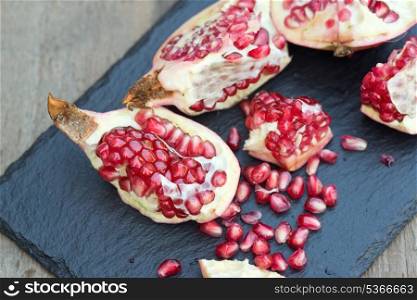 Fresh pomegranate sliced and ripped with seeds showing in rustic setting