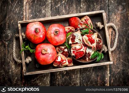 Fresh pomegranates on a tray. On a wooden background.. Fresh pomegranates on a tray.
