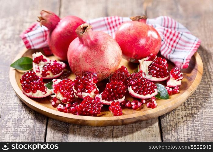 fresh pomegranates on wooden plate