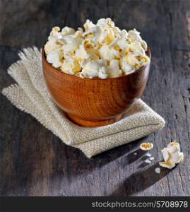 Fresh popcorn in bowl on old wooden table, isolated
