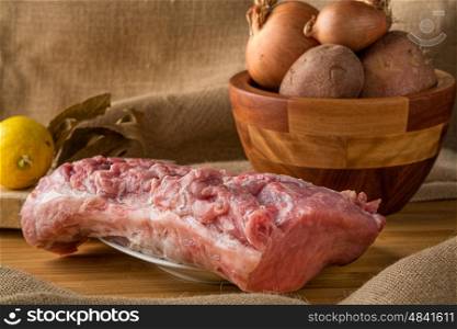 fresh pork loin over table with potatoes, garlic and lemon