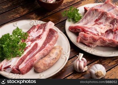 Fresh pork ribs, beef and criollo sausage on wooden table ready to be cooked on barbecue. Spanish Churrasco